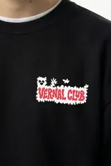 Buzo negro de corte oversize con estampado gráfico en la espalda que presenta la leyenda 'Vernal Club' y un personaje ilustrado con estilo underground.