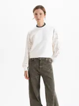 Buzo de calce regular con cuerpo de tela lisa y mangas largas de tejido calado con textura. Presenta escote redondo y puños ajustados.