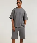 Bermuda masculina de algodón y poliéster, color gris oscuro, con cintura elástica y cordón ajustable. Presenta bolsillos funcionales.