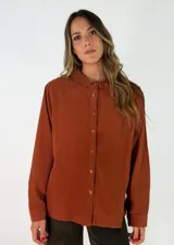 Camisa de pana color chocolate, con cuello alto tipo mao con volados, cierre frontal de botones y mangas largas con puños abotonados.