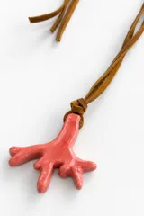 Gargantilla de cordón de cuero tostado con dije artesanal de cerámica en forma de coral de color rosado.