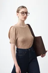 Remera negra de manga corta con textura floral en relieve. Presenta un diseño de inspiración romántica con mangas ligeramente abullonadas que aportan estructura y un ajuste al cuerpo.