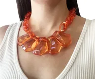 Collar corto de resina naranja translúcida con cadena de eslabones dorados.