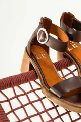 Sandalias de cuero color marrón con tira ancha sobre los dedos y tira con hebilla al tobillo. Tacón de madera.