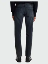 Jean de corte slim-fit en denim azul oscuro con efecto desgastado, cierre de botón y cremallera, y diseño de cinco bolsillos.