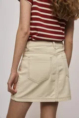 Falda de denim blanca de corte recto con bolsillos delanteros aplicados, costuras pespunteadas a contratono y cierre frontal con botón y cremallera.