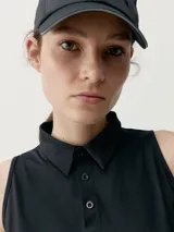 Musculosa polo deportiva negra con cuello mao y cierre frontal de tres botones.