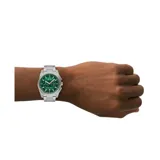 Reloj Armani Exchange con caja de acero plateado, esfera verde con detalles en naranja y correa de eslabones plateada.