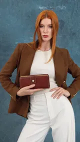 Billetera larga color tostado de diseño estructurado, confeccionada en símil cuero con cierre perimetral y solapa con broche a presión.