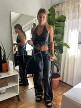 Pantalón negro de cuero sintético con flecos en los laterales.