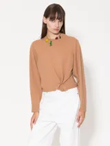 Sweater de lana merino color marrón, con cuello redondo, manga larga y detalle de frunce lateral con aro metálico en el frente.