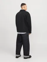 Campera estilo worker de color negro, con cierre frontal de cremallera, cuello clásico y dos bolsillos frontales. Presenta un diseño de corte recto y tejido liviano.