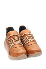 Championes deportivos acordonados de cuero, con diseño combinado en tonos beige, marrón y negro. Presenta suela de plataforma en color tostado y detalles metálicos en los ojales de los cordones.