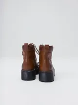 Bota de estilo trekking con diseño multicolor en tonos marrón, azul y detalles en rojo. Presenta plataforma de goma dentada, cordones tipo cuerda de escalada y cuello acolchado.
