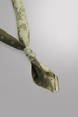 Bandana cuadrada confeccionada en tejido ligero de mezcla de ramio y algodón, con diseño de patchwork que combina paneles con estampados florales y paisley en tonos amarillo, mostaza y verde militar.