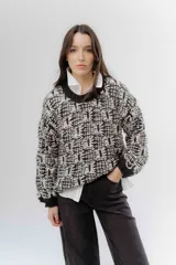 Buzo de tejido grueso con diseño artesanal bicolor en tonos marrón y crema. Presenta cuello redondo y terminaciones en rib en puños y cintura, con un calce relajado.