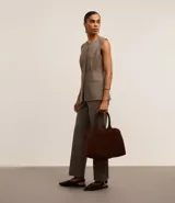 Chaleco regular color marrón claro con estampa de cuadros, confeccionado en punto roma, con cuello redondo, abotonado delantero con botones forrados y recorte en la bajo.