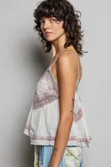 Top de algodón color rosado, con escote en V, tirantes finos, detalles de encaje bordado en el pecho y bajo asimétrico fluido.