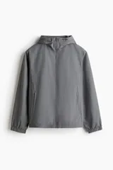 Campera rompevientos color gris, con capucha ajustable, cierre frontal y bolsillos laterales. Confeccionada en nylon repelente al agua con forro de malla interior.