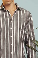 Camisa de manga larga en color salmón con estampado de pequeños motivos geométricos oscuros, cuello clásico y cierre frontal con botones.