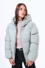 Campera puffer de corte holgado en color beige, con capucha integrada, cierre frontal completo y bolsillos laterales. Presenta un diseño acolchado con acabado mate y puños elásticos.