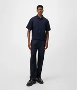 Pantalón de jean azul marino con corte recto y estilo semi sastrero, confeccionado en denim crudo de algodón, con pinzas frontales y trabillas para cinturón.