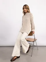 Sweater de punto con diseño de trenzas verticales, cuello alto y silueta oversize. Presenta un patrón bicolor en tonos azul y azul oscuro, con mangas largas y terminaciones en tejido acanalado.