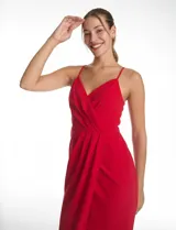 Vestido midi de crepe color rojo, con escote en V cruzado y drapeado en el busto. Presenta una falda envolvente con diseño drapeado que genera una abertura asimétrica en el bajo. Cuenta con tirantes finos y cierre invisible en la espalda.