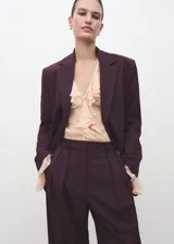 Pantalón de vestir bordó de tiro medio, con diseño wide leg, pinzas en la parte delantera, bolsillos laterales y cierre frontal con botón, gancho y cremallera.
