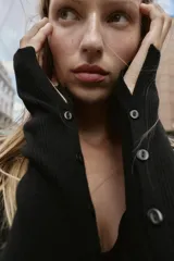 Vestido midi negro de tejido de punto acanalado, manga larga y escote corazón. Presenta una hilera de botones decorativos en el frente y una abertura en el bajo.