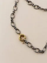 Collar de cadena larga con eslabones ovalados alargados y cierre tipo sailor clasp, con dije colgante en forma de corazón de piedra oscura. Acabado dorado.