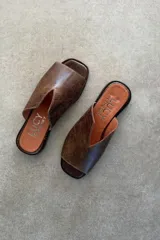 Sandalias chatitas de cuero vacuno color gris azulado, con diseño destalonado y capellada envolvente con abertura en V.