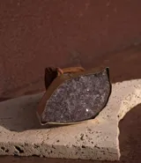 Cinto de cuero marrón camel con hebilla metálica ancha adornada con una piedra natural de amatista facetada.