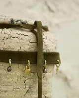 Gargantilla tipo choker de gamuza con dijes colgantes artesanales de metal y perlas naturales. Cuenta con tiras largas para atar y ajustar en la parte posterior.