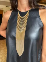 Collar de diseño llamativo compuesto por múltiples capas de cadenas doradas y barras metálicas verticales que descienden en un fleco largo y fluido.