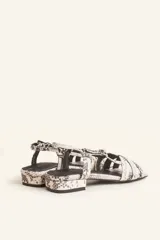 Sandalias bajas con estampado de piel de serpiente en tonos blanco y negro. Tiras finas entrecruzadas en el empeine, pulsera al tobillo con hebilla ajustable y pequeño tacón cuadrado.