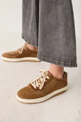 Zapatillas de cuero con textura de pelo, color marrón, con suela de goma color crema y cordones gruesos con diseño trenzado.
