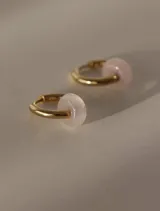 Aros de acero quirúrgico dorados en forma de argolla con dijes de piedra natural negra en forma de dona, desmontables.