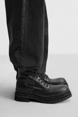 Bota negra de cuero con cordones, caña media y suela track.