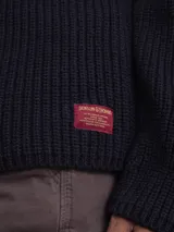 Sweater de punto grueso color azul marino, con cuello alto y cierre frontal de botones.