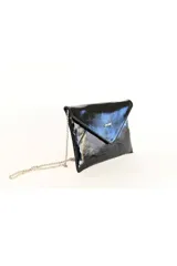 Sobre de mano tipo clutch confeccionado en charol negro brillante con solapa geométrica y cadena metálica plateada delgada.