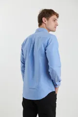 Camisa de vestir blanca de manga larga, con cuello abotonado, bolsillo frontal y botones en tono madera.