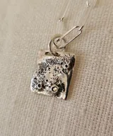Collar de plata 950 con cadena de eslabones alargados y dije rectangular con textura irregular inspirada en la superficie lunar.