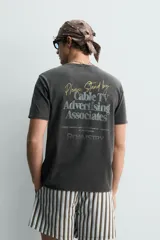 Camiseta de corte relajado con efecto lavado, cuello redondo y manga corta. Presenta estampados con textos en contraste en el frente.