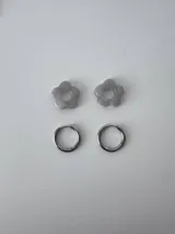 Aros de acero quirúrgico argolla con dije colgante en forma de flor de resina color gris marmoleado.