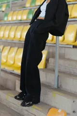 Pantalón negro de gabardina elastizada, corte sastrero, tiro bajo y pierna ancha. Tiene bolsillos delanteros, botón metálico con logo RENÉE y tajo en el lateral interno.