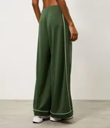 Pantalón deportivo ancho de color verde oscuro, de talle alto con cintura elástica y detalles de vivos en color blanco en los laterales y la botamanga.