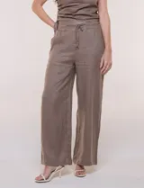 Conjunto de dos piezas de lino verde oscuro, compuesto por un top de un solo hombro con arandela decorativa y un pantalón palazzo de tiro alto con cintura elástica y bolsillos.