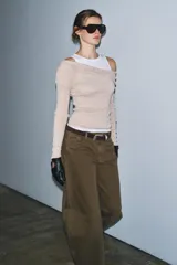 Camiseta de manga larga gris melange con cuello redondo y diseño asimétrico que simula una doble camiseta, con una capa inferior blanca visible en el cuello y el bajo.