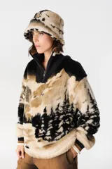 Buzo de peluche con estampado de paisaje montañoso en tonos beige, negro y blanco. Presenta cuello alto con cierre frontal, mangas largas con puños tejidos acanalados y corte holgado.